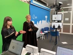 Kaksi henkilöä seisoo studion edessä tulostaulun äärellä.