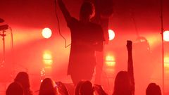 Esiintyjä lavalla yleisön edessä punaisessa valaistuksessa.