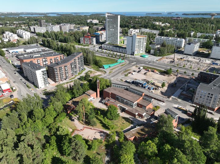 Ilmakuva, jossa näkyy puita, rakennuksia, rakennustyömaita ja teitä.