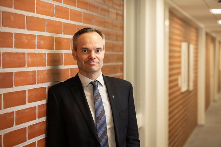 Kaupunginjohtaja Kai Mykkänen seisoo tiiliseinän edessä.