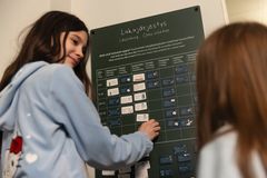 Kaksi ihmistä seisoo lukujärjestystaulun edessä.