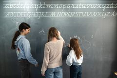 Kolme ihmistä seisoo selin liitutaulun edessä kirjoittamassa.