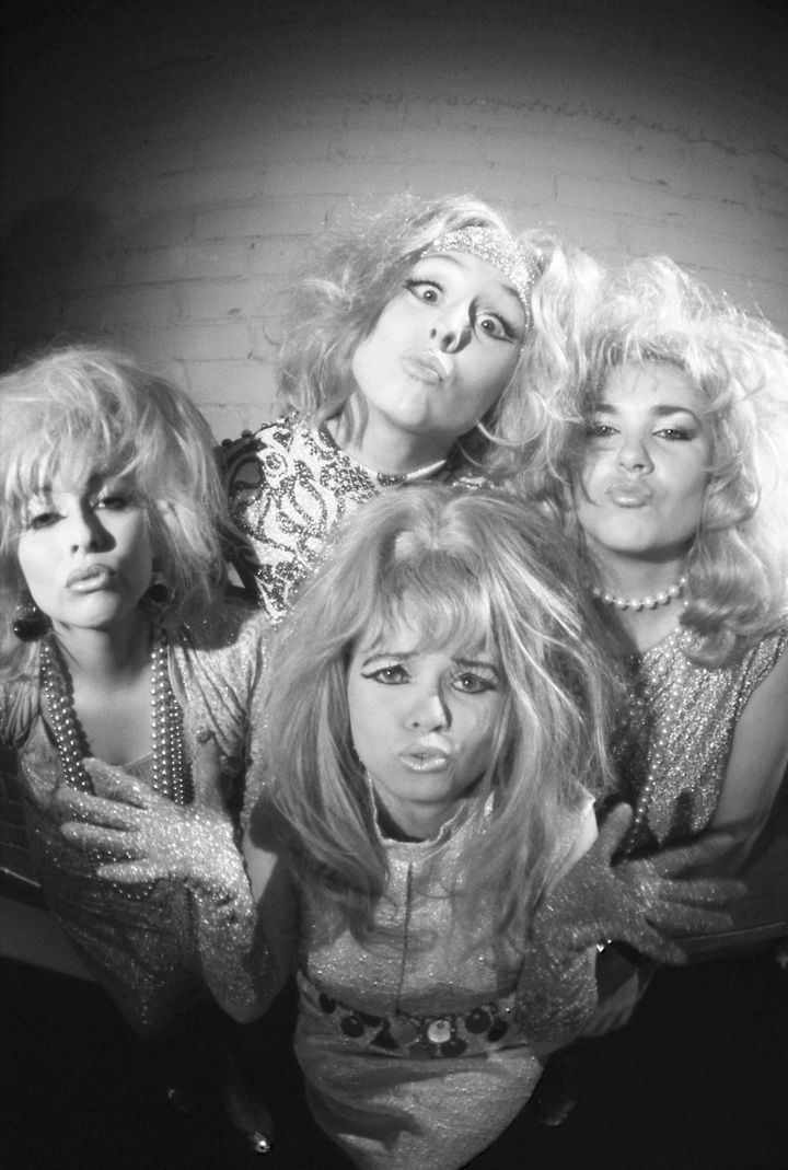 Neljän naista seisoo hauskasti ryhmässä mustavalkoisessa kuvassa.