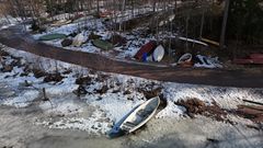 En snöig strand vid Långträsk med flera båtar på rad.