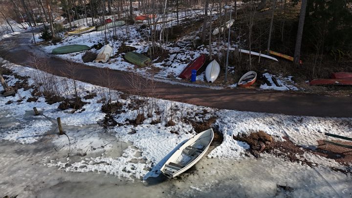 En snöig strand vid Långträsk med flera båtar på rad.