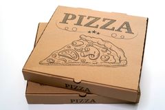 Kaksi ruskeaa pahvista pizzalaatikkoa päällekkäin vaaleaa taustaa vasten.