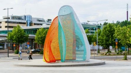 Värikäs verkkomainen veistos kaupunkiaukiolla.