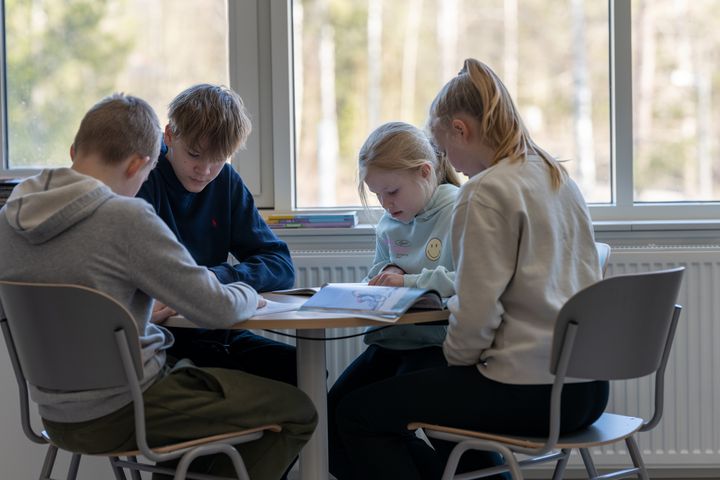 Espoolaiset peruskoulun oppilaat istuvat yhdessä pöydän ääressä.