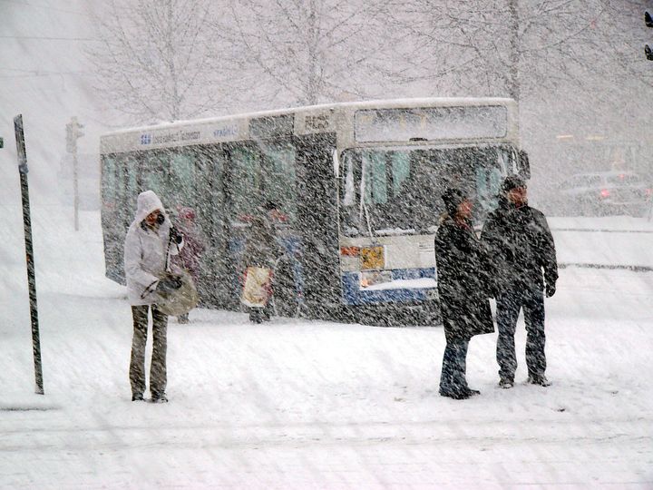 Matkustajia odottamassa bussia talvella.