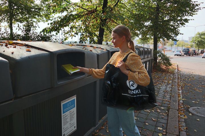 Henkilö kierrättää ekopisteellä.