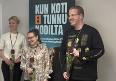 Kolme henkilöä seisoo vierekkäin ja pitelee kukkia; kuvassa ovat Ensi‑ ja turvakotien liiton uudet hallituksen jäsenet Hanna Hämäläinen, Marianna Roine ja Elias Janhunen.