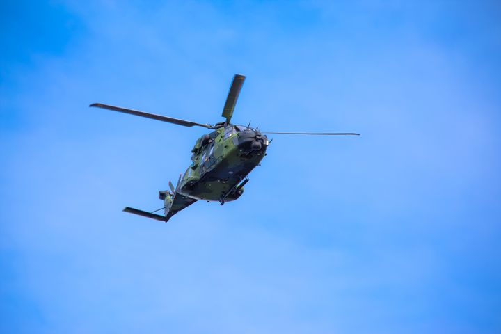 Helikopteri lentää sinistä taivasta vasten.