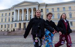 Kolme opiskelijaa kävelee Helsingin yliopiston päärakennuksen edessä.