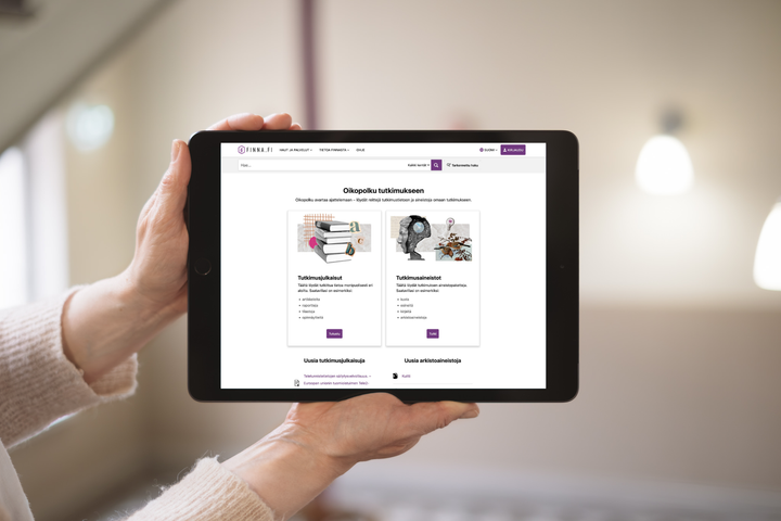 Kädet pitävät tablettia, jossa näkyy tutkimusaiheinen verkkosivu.