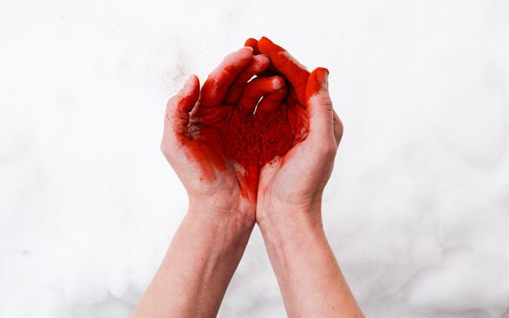 Punamultapigmenttiä kämmenissä lumihankea vasten.