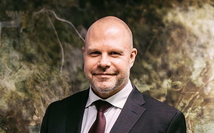Tapio Lahtero tummassa puvussa metsäisen taustan edessä.