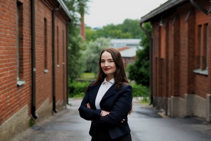 Pinja Ryky seisoo ulkona kahden tiilirakennuksen välissä.