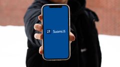 Personen visar telefonskärmen som visar mobilapplikationen Suomi.fi