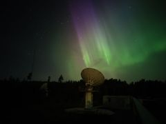 Revontulia yötaivaalla, etualalla teleskooppi.