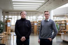 Kuvassa kaksi miestä seisoo kirjastossa.
