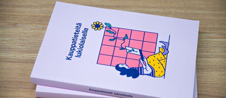 Kaksi pinkkiä kirjaa, joissa teksti "Kauppatieteitä lukiolaiselle" ja kuva naisesta istumassa ikkunan edessä.