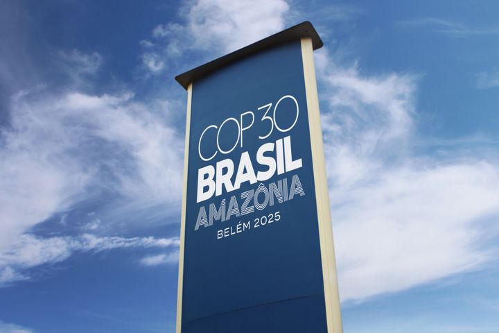 Tekstikyltti, jossa lukee: "COP30 Brasil, Amazônia, Belém 2025". Kyltti on sinistä taustaa vasten.