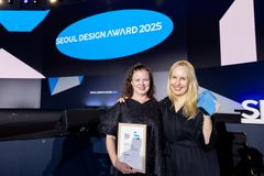 Kaksi henkilöä hymyilee, kädessä palkintokirja, taustalla teksti Seoul Design Award 2025