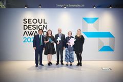Henkilöitä seisomassa lavalla palkintokirja kädessä, taustalla teksti Seoul Design Award 2025