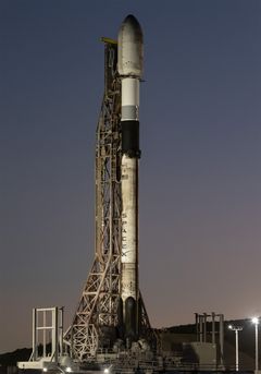 A rocket is on a launch pad at dusk, ready for launch.