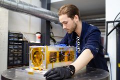 Mies työskentelee laboratoriossa satelliitin parissa.