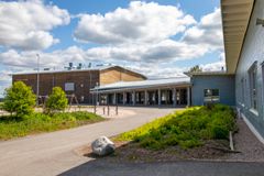 Koulurakennus pilvisellä säällä, edustalla leikkivälineitä ja viheralue.