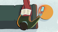 Henkilö istuu sohvalla, lukee kirjaa ja samalla katsoo älypuhelinta.