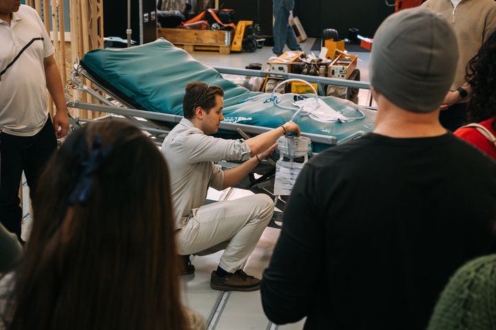 Kuvassa henkilö esittelee älykkään virtsanerityksen seurannan mittausprototyyppiä sängyn vieressä yleisölle.