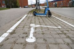 Kuvassa maahan piirretty valkoisella rajat sekä potkulautaa esittävä kuva. Rajojen sisällä on yksi potkulauta parkattuna.