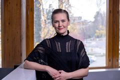 Ystävällisen näköinen henkilö seisoo ikkunan edessä, yllään musta paita.
