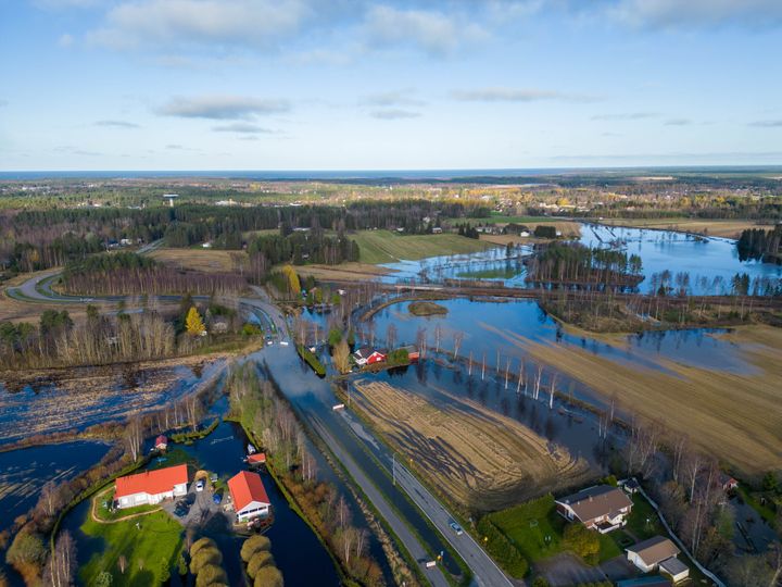 Ilmakuva tulvivista pelloista ja rakennuksista vesistöjen ympäröimänä.