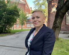 Annareetta Vaara seisomassa ulkona tiilirakennuksen edessä.