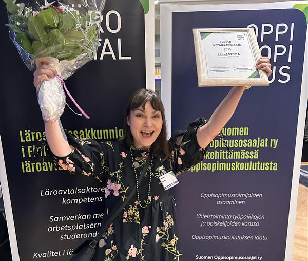 Sanna Nerola juhlii Vuoden työpaikkaohjaaja -palkinnon kanssa pitäen kukkakimppua ja palkintoa kädessään.