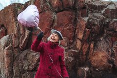 Nainen katsoo hymyillen kädessään olevaa pinkkiä ilmapalloa.
