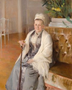 En person sitter i en soffa med en promenadkäpp i handen.