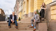 Kolme henkilöä kuvattuna Valtioneuvoston linnan kivisillä ulkoportailla Helsingin Senaatintorilla.
