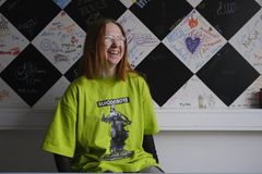 Nuori seisoo mustavalkoisen seinän edessä ja hymyilee