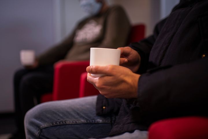 Henkilö istuu kahvikuppikädessä odotushuoneessa.