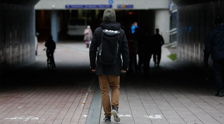 Reppuselkäinen henkilö kävelee tunnelissa.