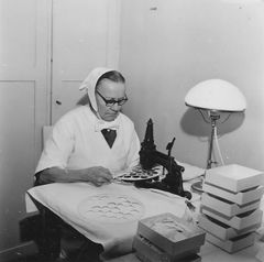 Nainen leikkaa pienellä koneella pyörästä levyst'ä irti ehtoollisleipäkuviota.