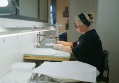 Nainen leikkaa koneella irti ehtoollisleipiä paistetusta levystä.