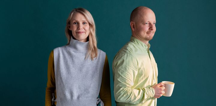 A woman and a man standing side by side, the man holds a mug.