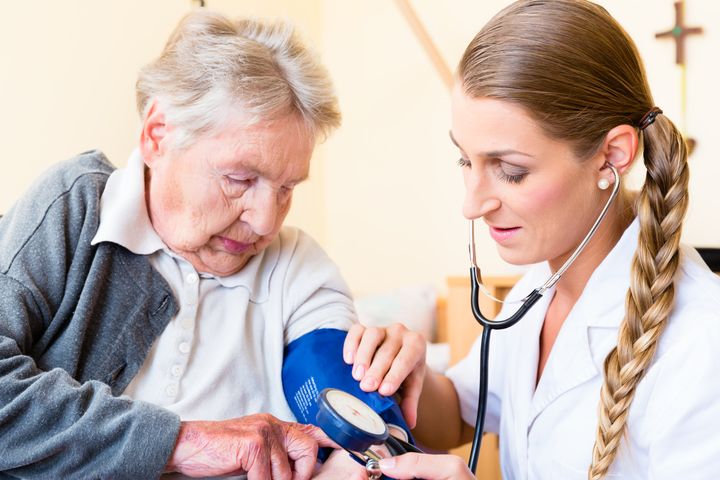 Terveydenhuollon ammattilainen mittaa verenpainetta vanhukselta.