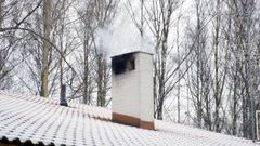 Talon katolla olevasta savupiipusta tupruaa savua.