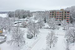 Harmaa ilmanlaadun mittausasemakontti sijaitsee risteyksessä puun alapuolella ja vastapäätä näkyy kerrostalo.